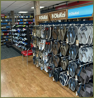 Display of sandals in a store with 'OluKai' branding | Boots & Soles